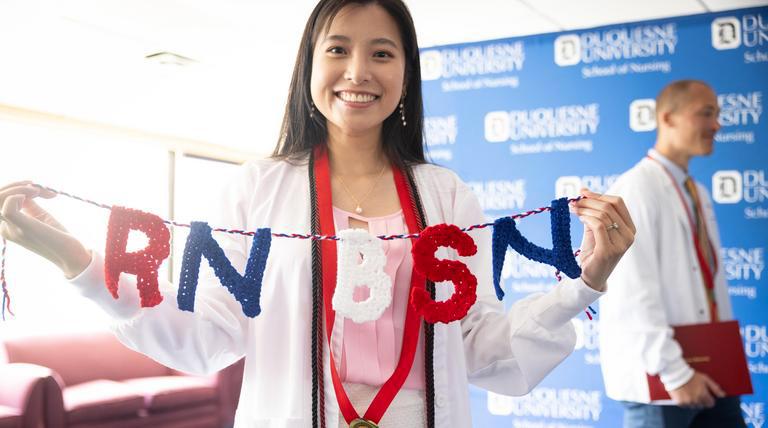 A Duquesne University nursing student holding up RN BSN letters