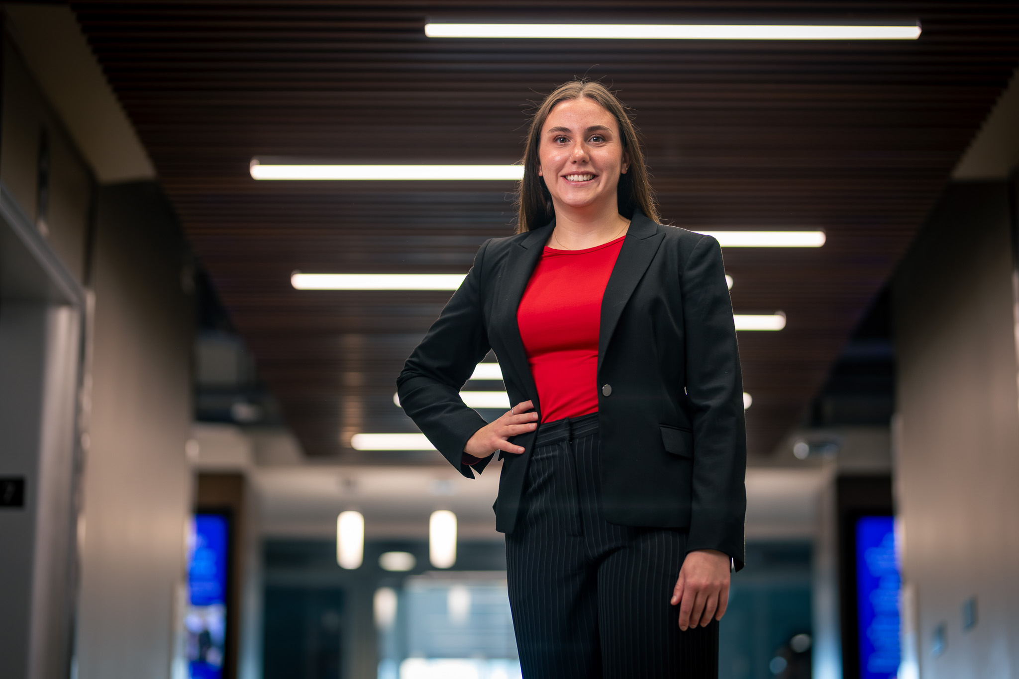 A business student wearing a suit stands with her hand on her hip.