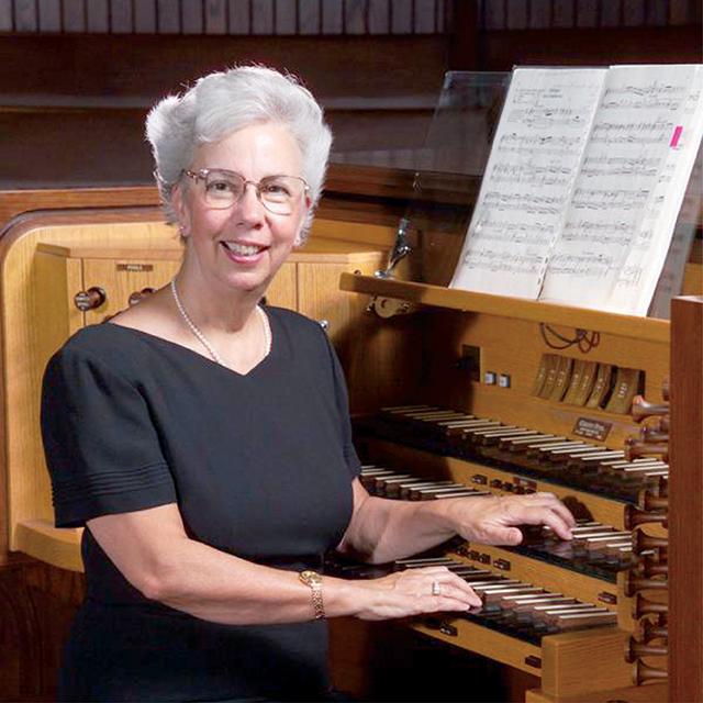 woman in black dress sits at an organ