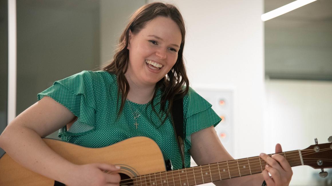 Rachel Anderson playing guitar in a music therapy setting
