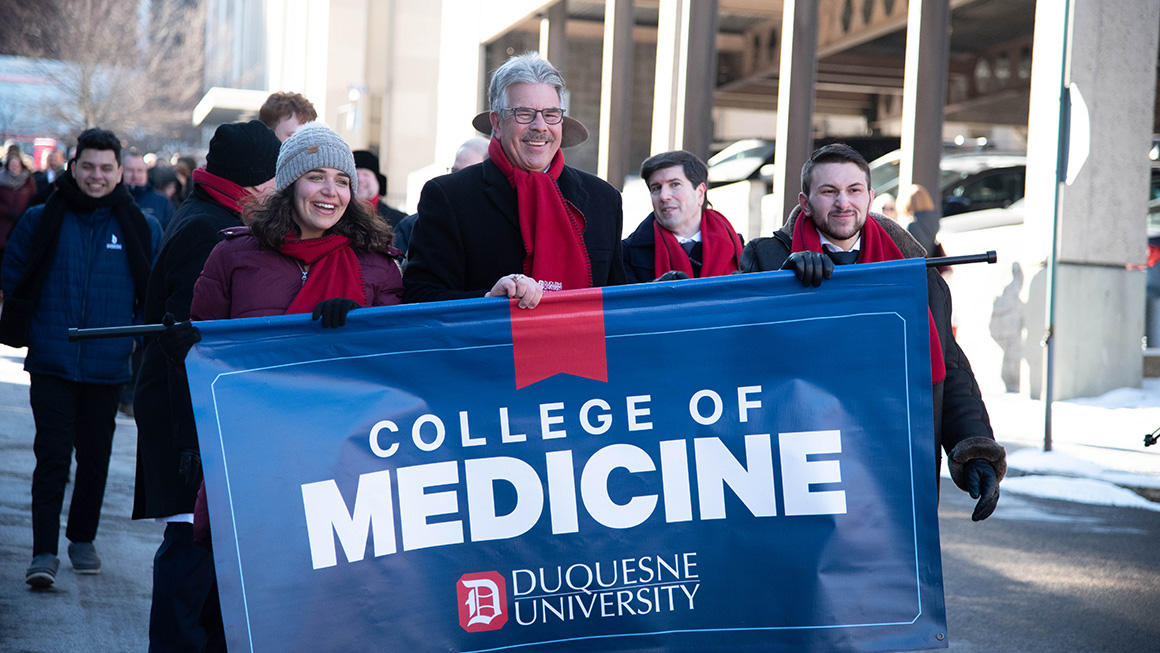 President Gormley carrying banner at the College of Osteopathic Medicine opening.