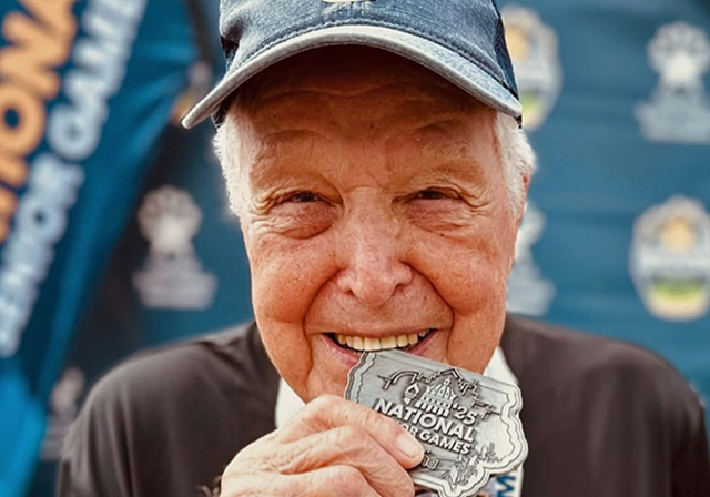 Jack Eckonrode biting a medal at the senior olympics.