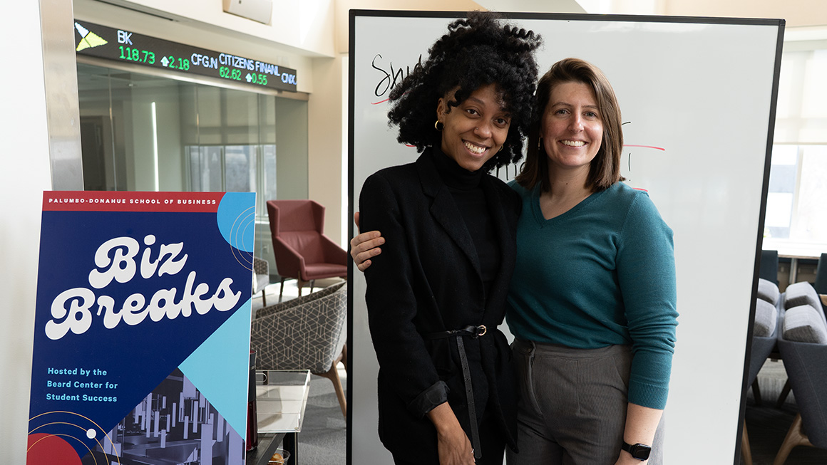 Success Coaches Shakeria Carter (left) and Michelle Curry (right) handing out coffee and donuts during a midterm BizBreak.