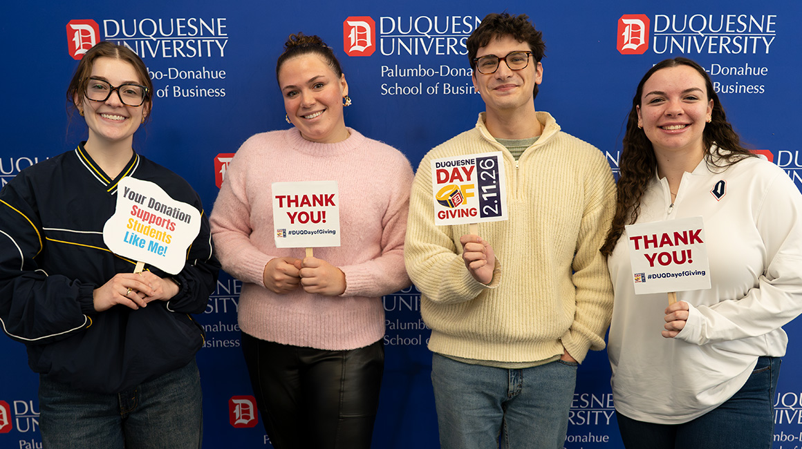 Four students holding thank you signs.