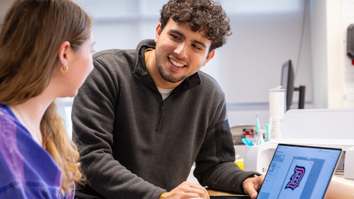 Two happy students looking at a computer together.