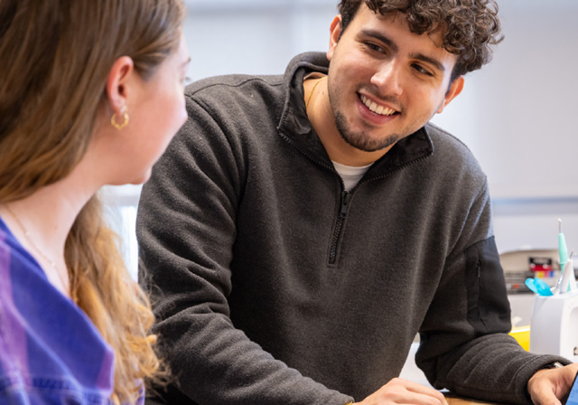 Two smiling students working on a laptop