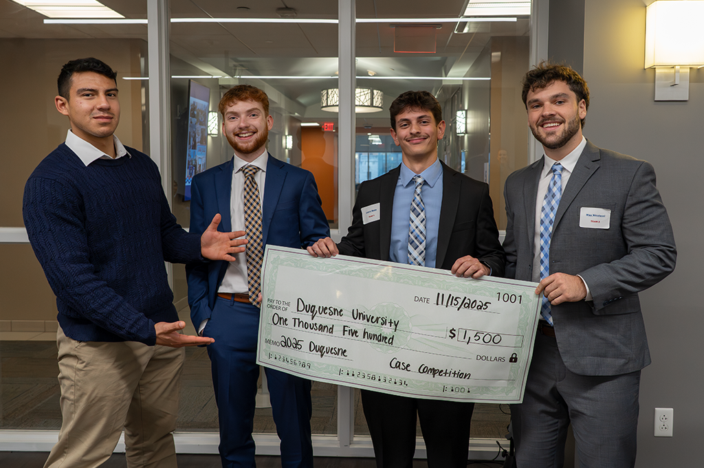 Professionally dressed students pose with a novelty check.