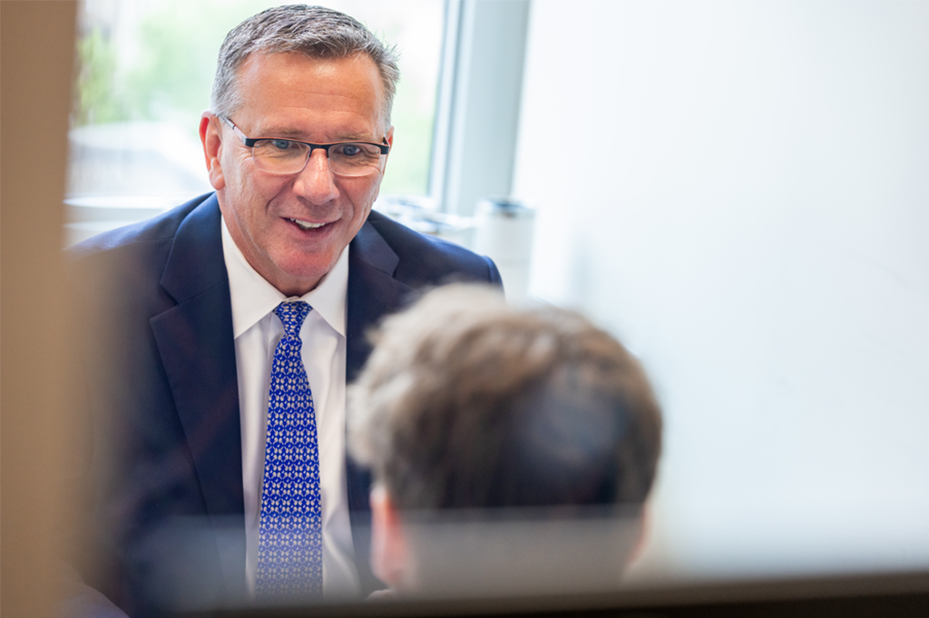 A professional mentor smiles as he meets with a student.