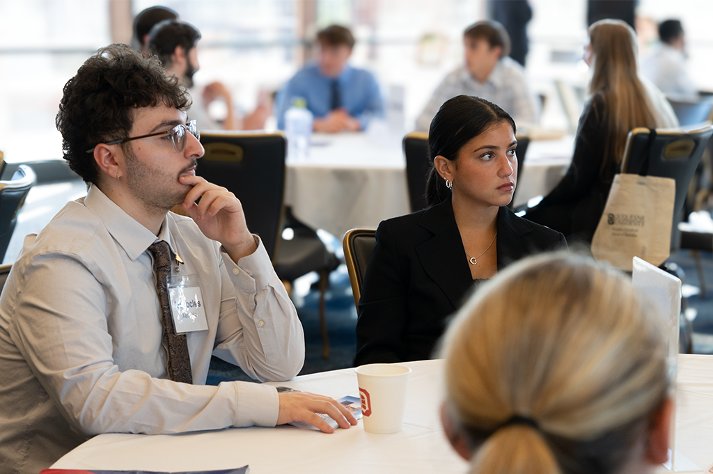 Students sit at a round table at a business networking event.