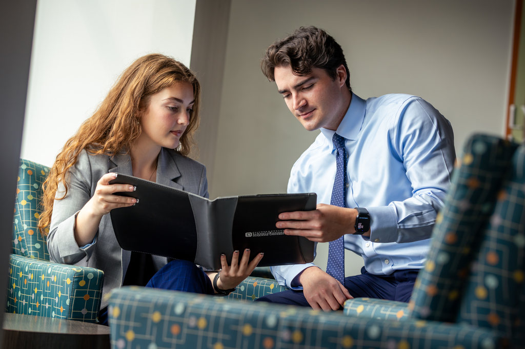 Two business professionals review documents in a padfolio.
