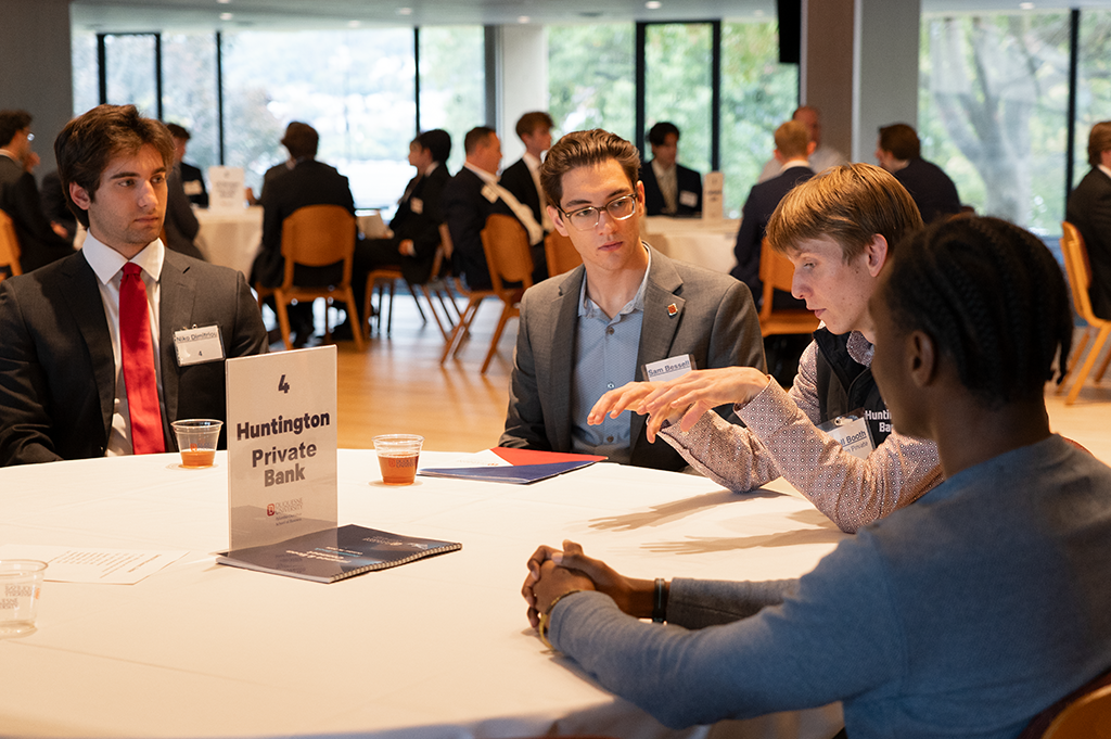 Business students listen to a professional talk at a networking event.