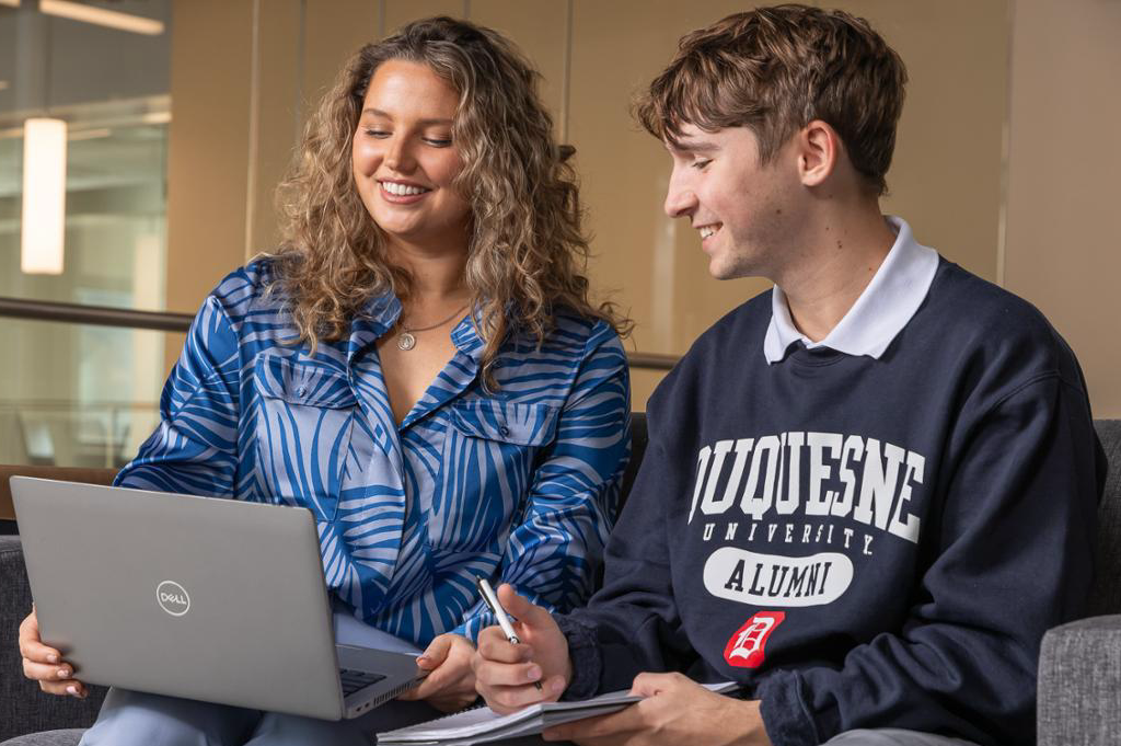 Accounting students collaborate on a laptop.