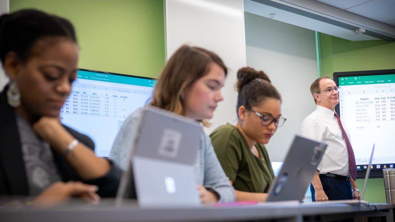 Three students focus in a finance class. 