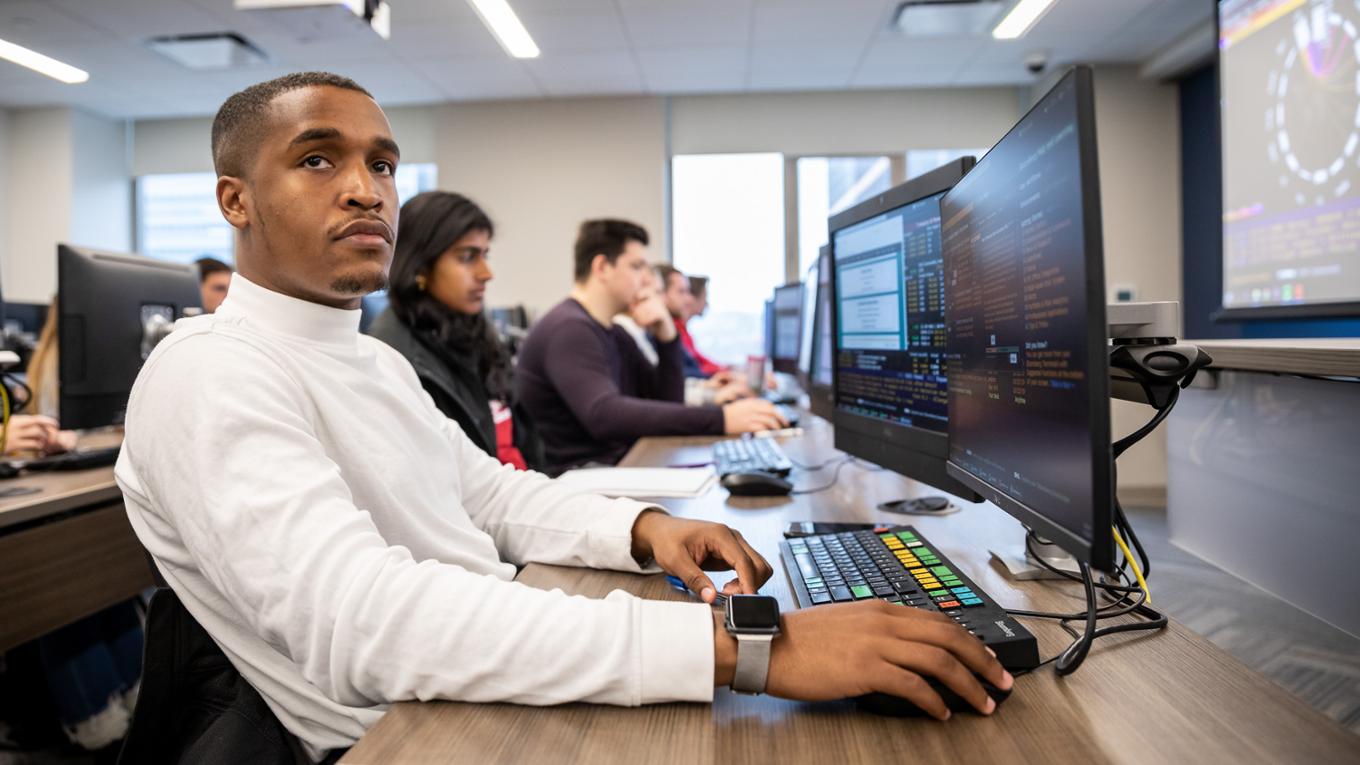 Student sits in front of a computer and listens attentively.