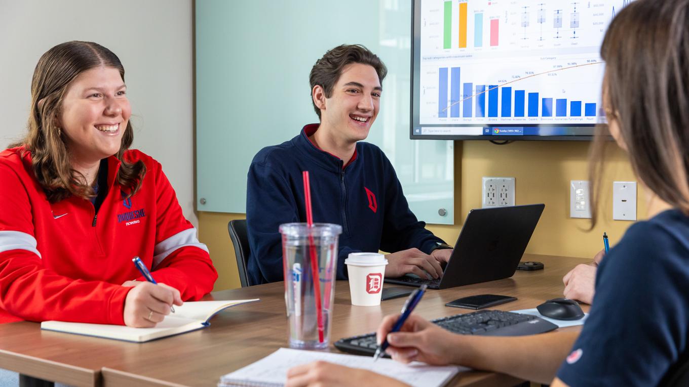 Three students study together at a table. 