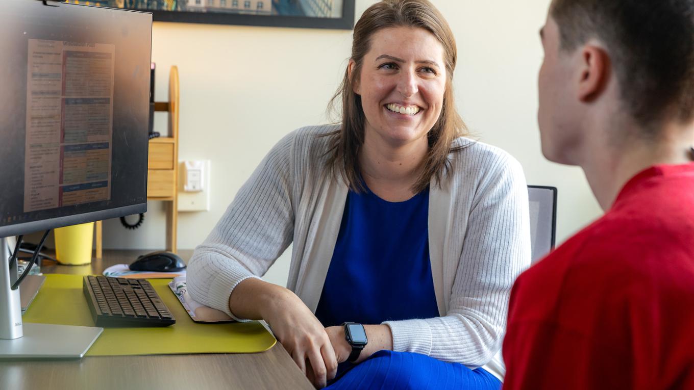 A Student Success Coach smiles while meeting with a student. 