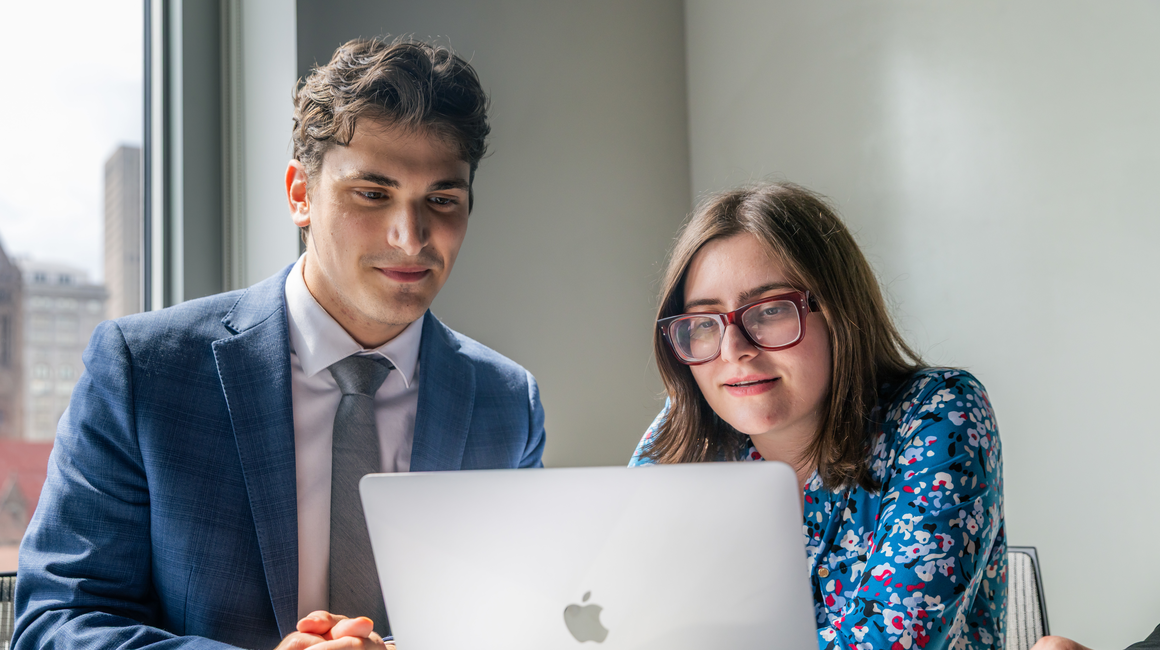 Two business professionals face a laptop.