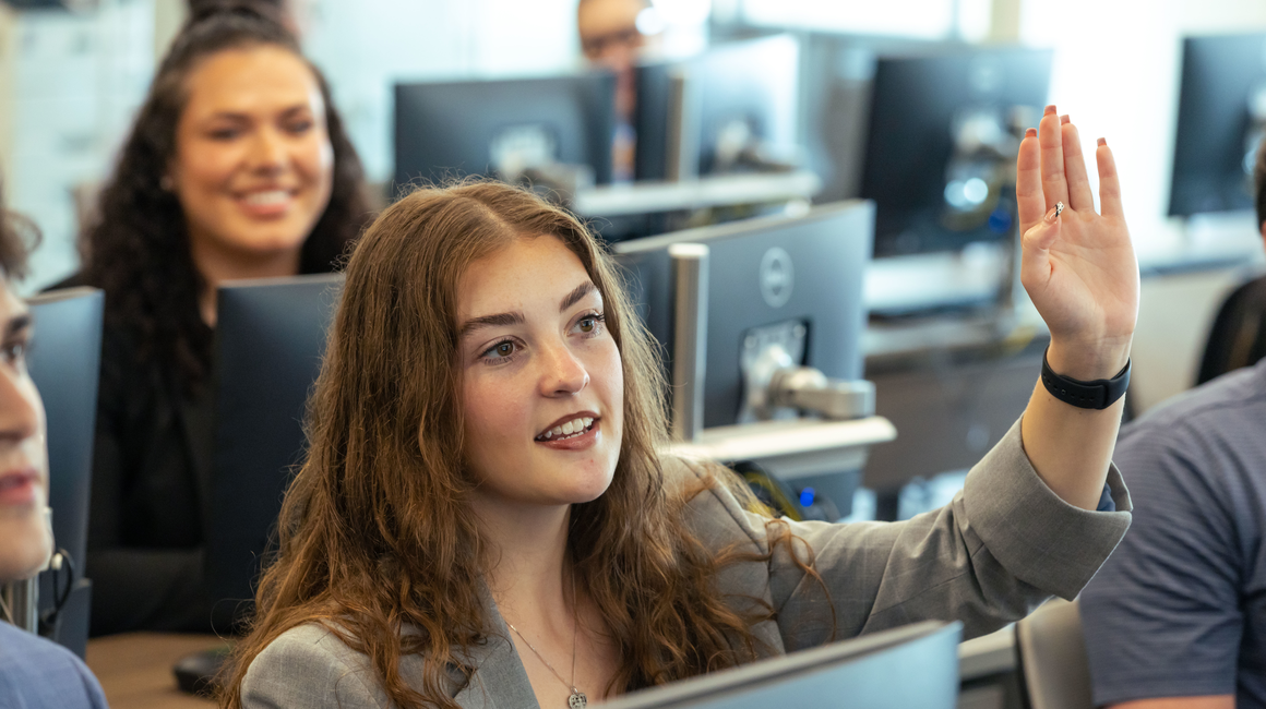A business student raises her hand in class.
