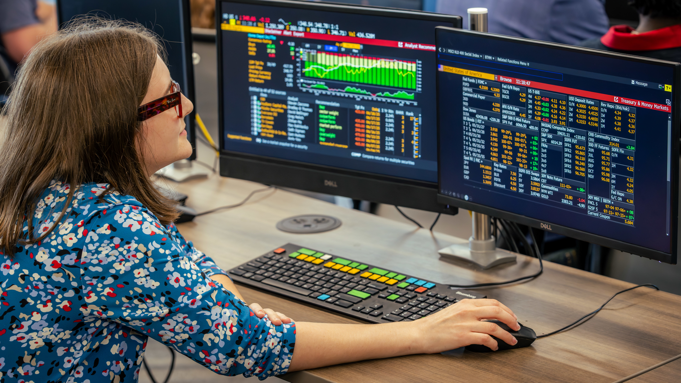 A graduate student works on a Bloomberg terminal in a finance lab.