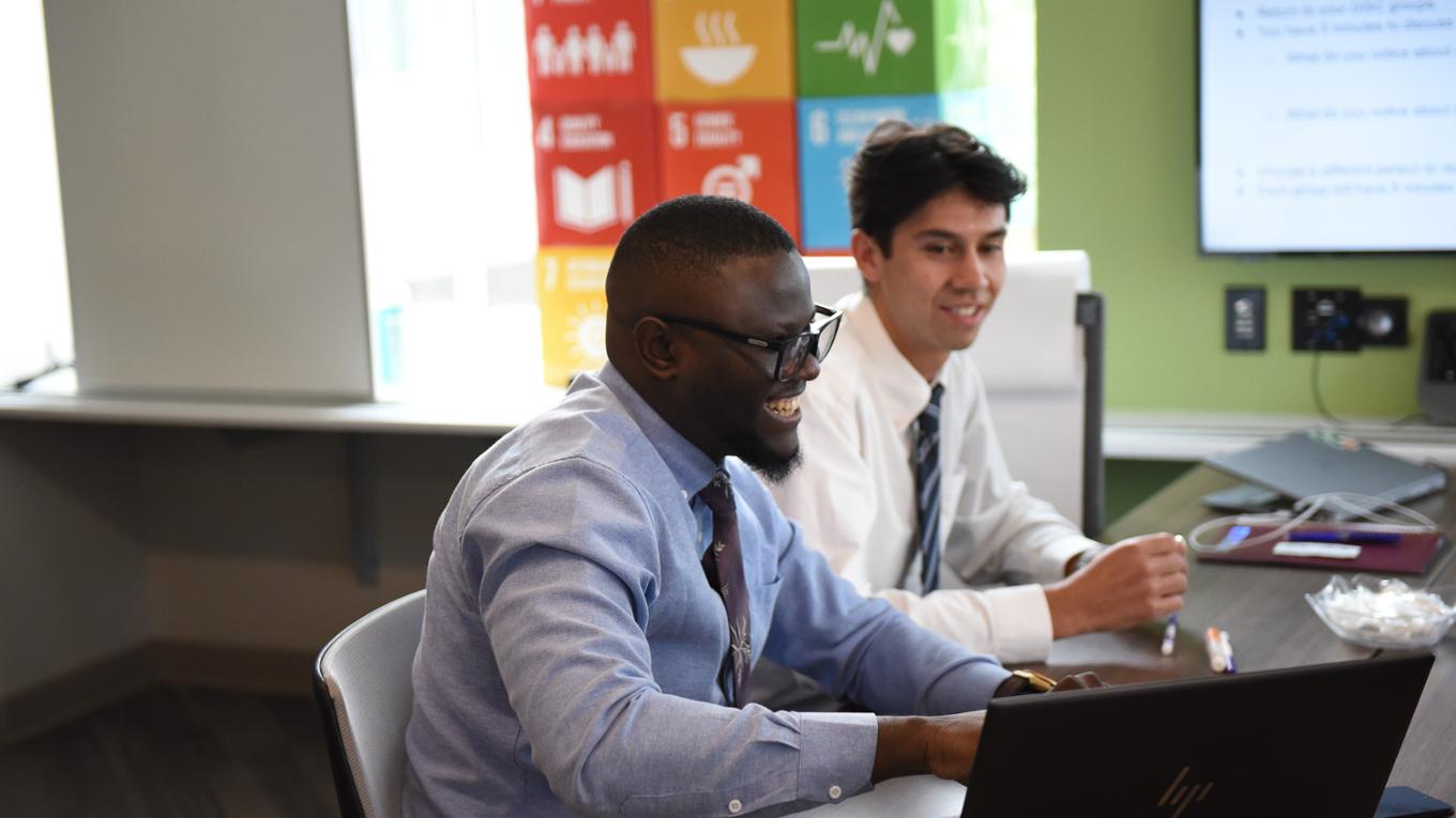 Two mba students collaborate at a table.