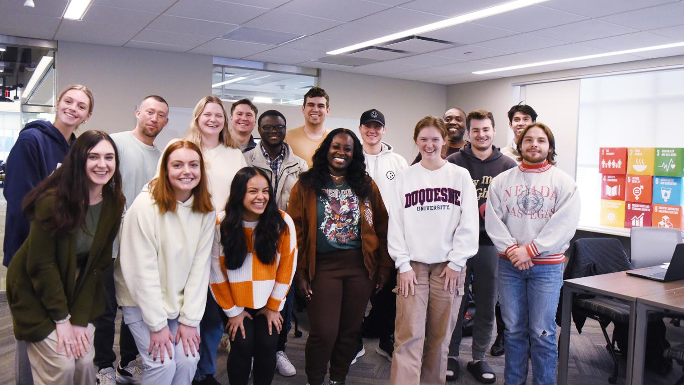 A group of MBA students smile in a classroom.