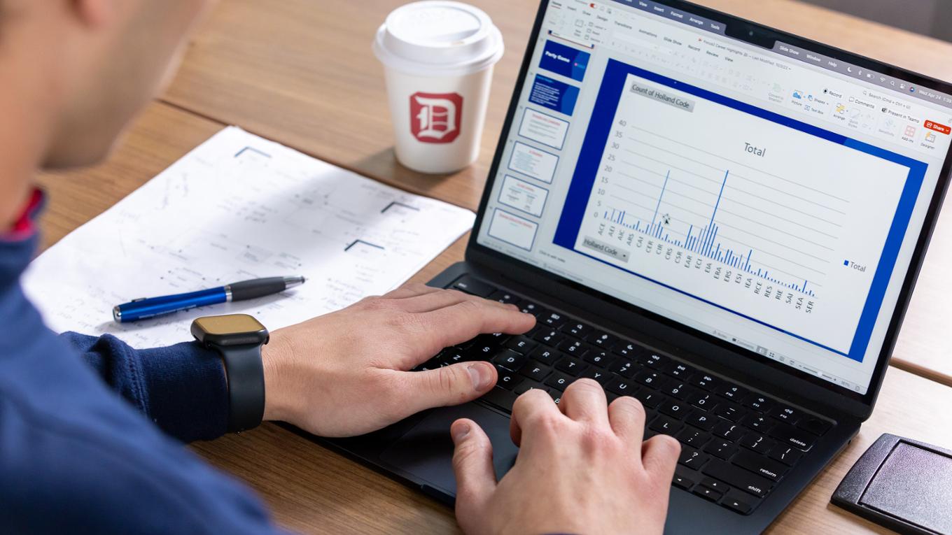 Close up of a student typing on a laptop which is showing a bar graph.