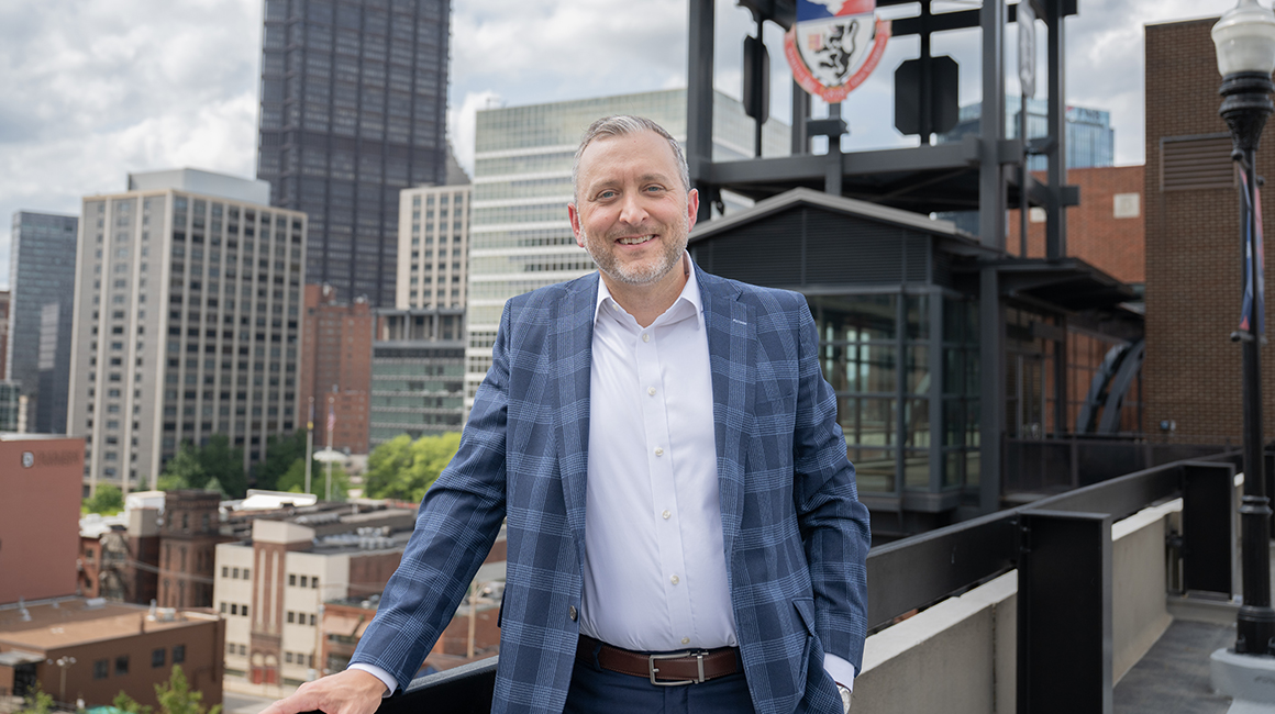 Kevin Lewis standing in front of Duquesne sign.