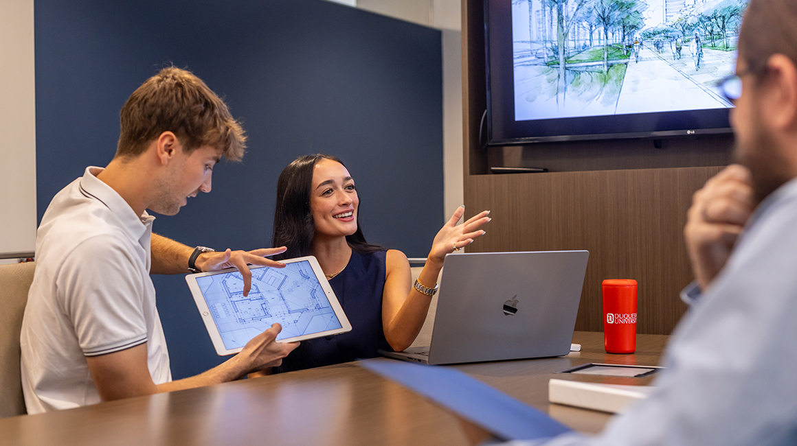 Duquesne students working together on a project in a conference room.