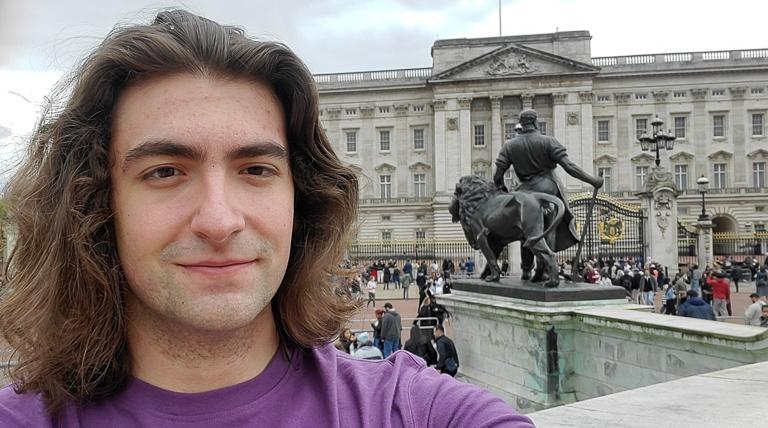 Photo of School of Education Study Abroad student Antonio Batista in Italy outside with Italian building and statue behind him and people on the sidewalk