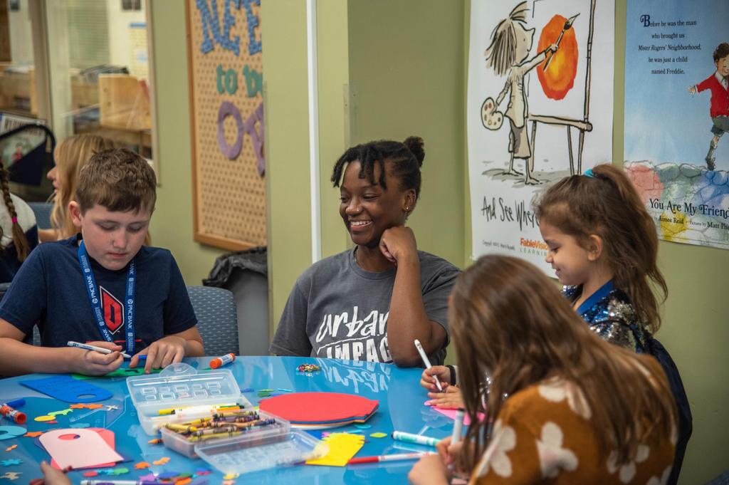 School of Education undergraduate student works at a table with children in the University's Curriculum Center.