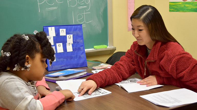 A Duquesne School of Education works with a young student on a reading assignment.