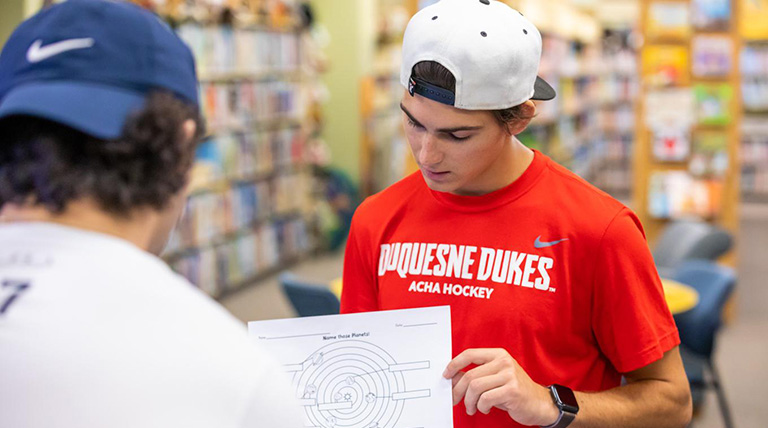 A Duquesne School of Education shows a graph to another student.