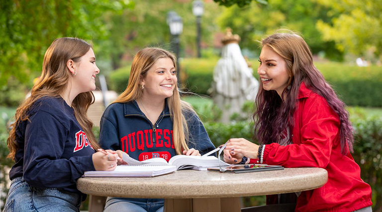 Duquesne School of Education students studying together outside on campus