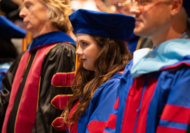 Doctoral students and faculty in graduation regalia at hooding ceremony