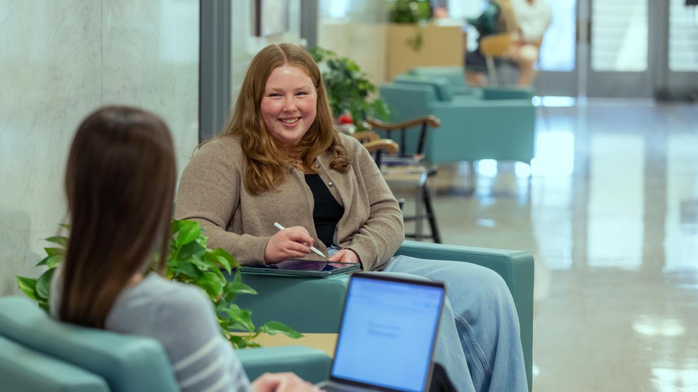School Supervision Certification Program graduate student sitting and collaborating with colleague in Pennsylvania school hallway.