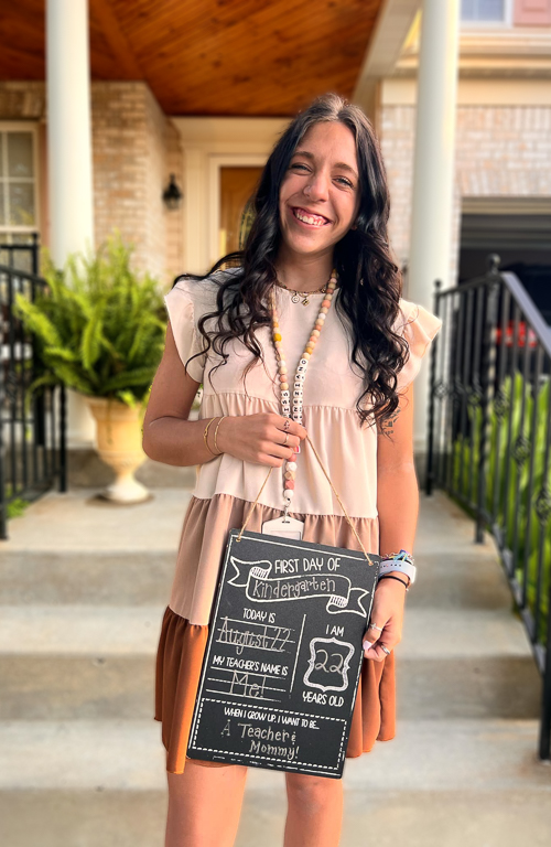 Photo of School of Education alum Caterina Veneziano with first day of school sign outside