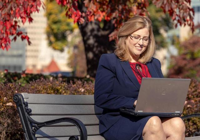 Woman sitting on bench with a laptop.