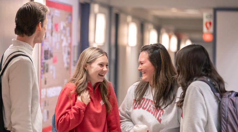 Students gathered in a hallway conversing.