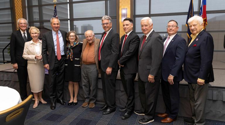 Nine people standing and smiling with Judge Guido Calabresi
