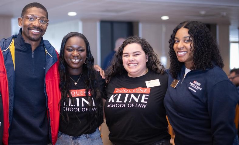 Four people standing and smiling