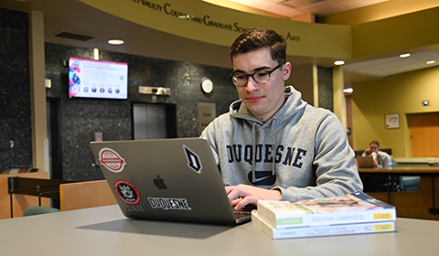 Ryan Stoudt uses his computer in the second floor College Hall lobby.