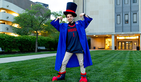 Daymond Kovaly wearing graduation robe with Duke mascot attire.