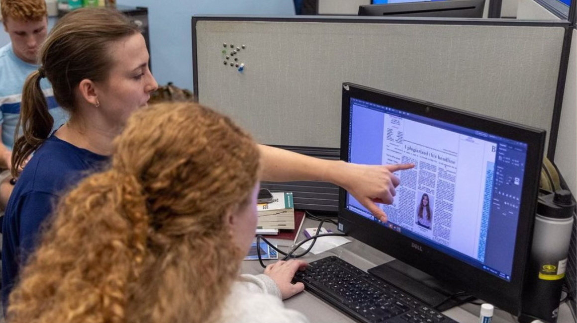 Student journalists from the Duquesne Duke working on a computer