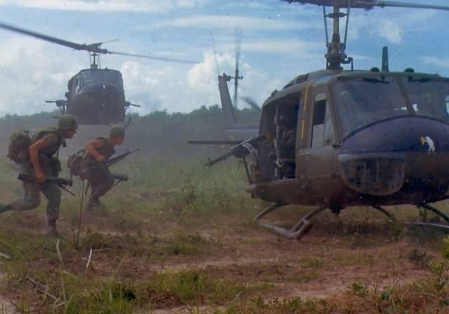 Two army men running into a helicopter