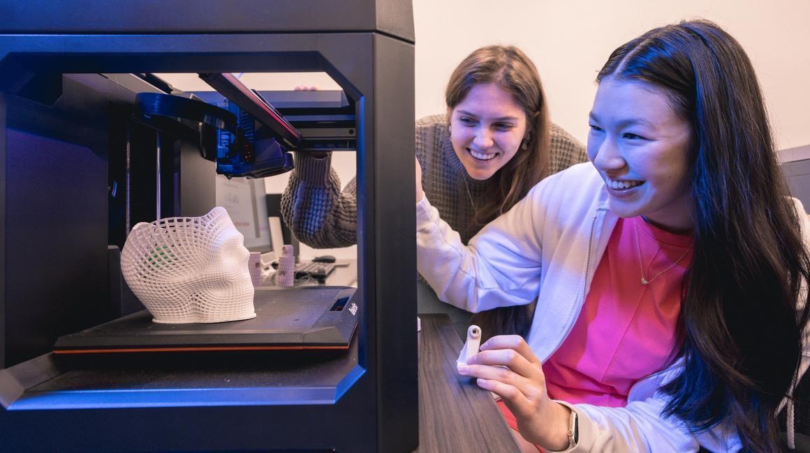 Two students use 3D printer to create a skull.