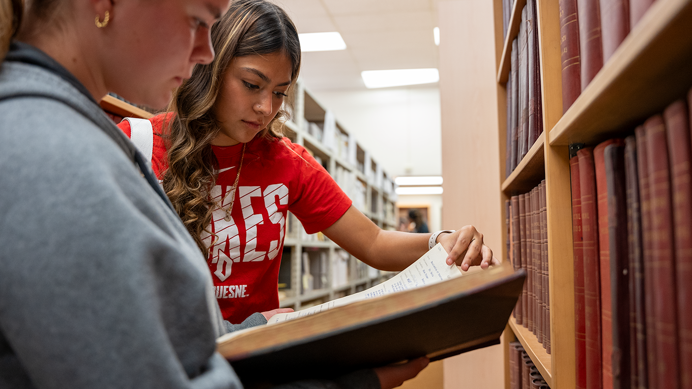 Two students reading book in archives.