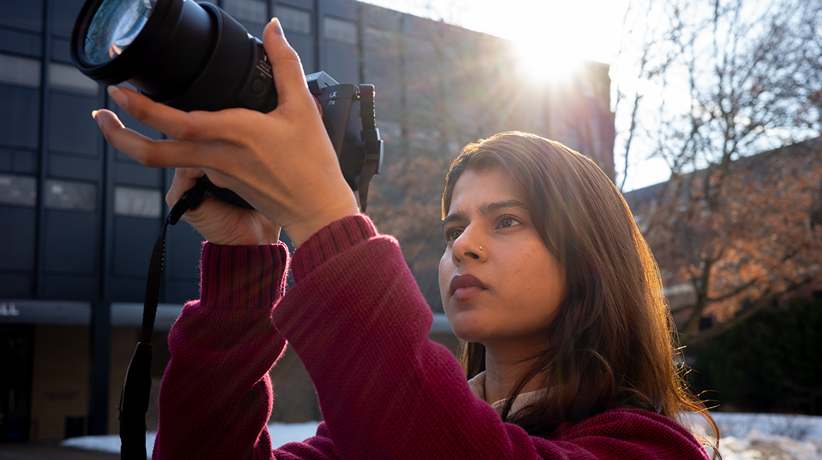 Student holds camera in the air while taking a photo.