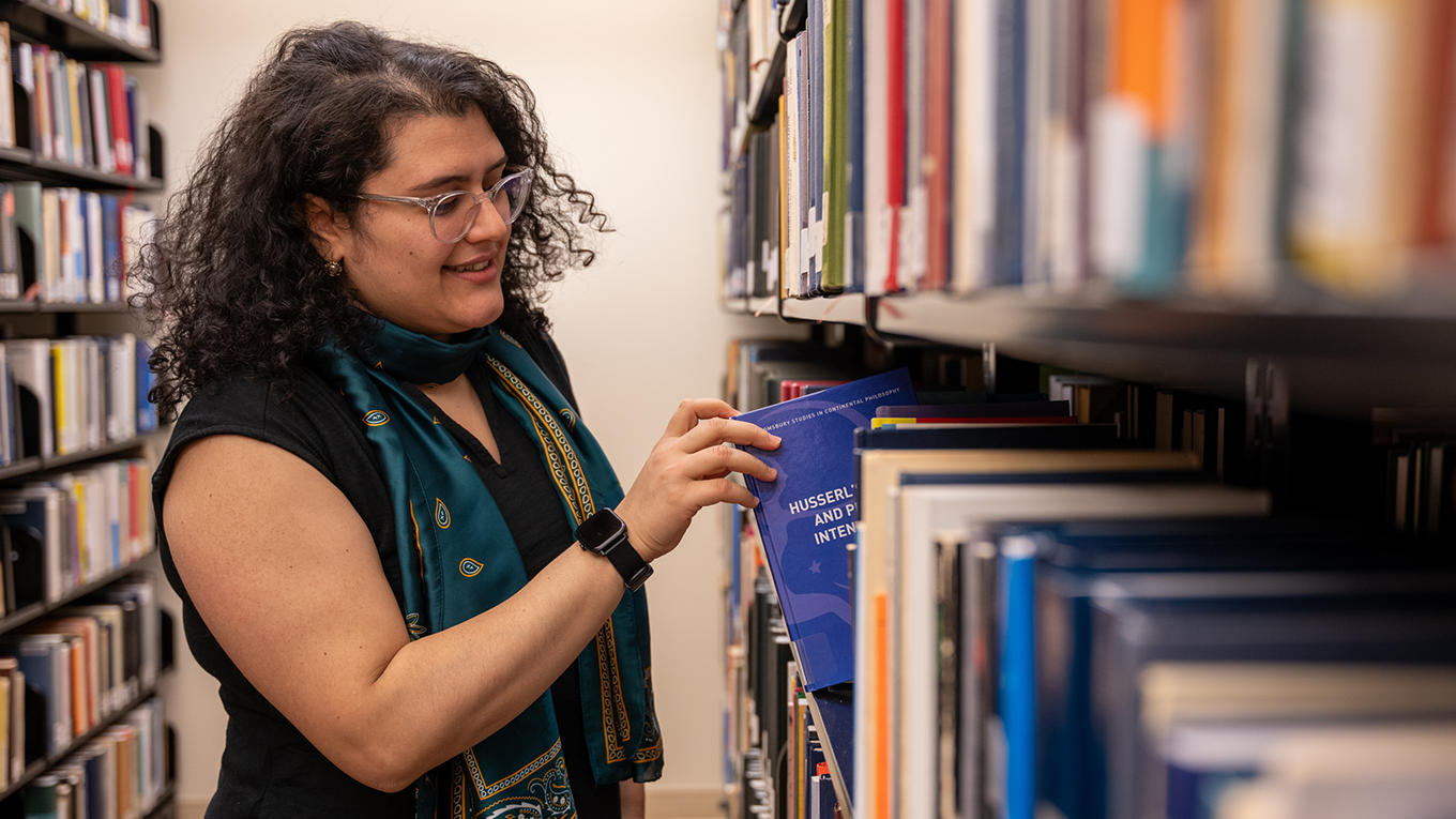 Student finding book on shelf in Silverman Phenomenology Center