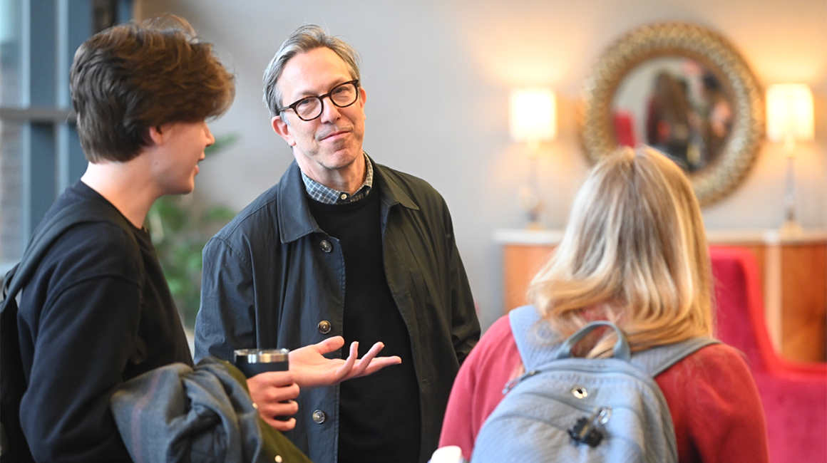 Two students chat with professor after English lecture.