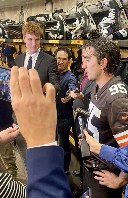 Spencer Thomas interviews a Pittsburgh Penguins player in the team's locker room.